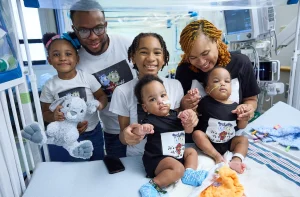 Parents and older siblings happily hold the hands of little brothers, following the surgery to separate the conjoined twins.