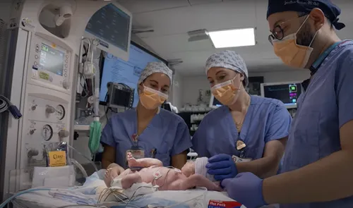 Caregivers help a newborn in the delivery room