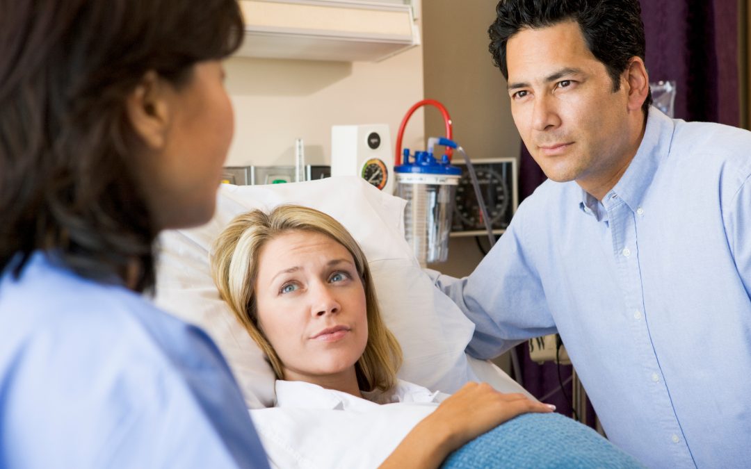 Doctor has serious conversation with pregnant mom and dad over a hospital bed
