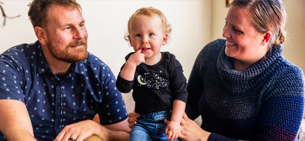 tabone family Mom and dad smile at one-year old daughter