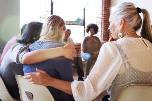 Support group sits in a circle, comforting each other 