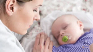 Mom looks at sleeping baby in a quiet moment of calm. Understanding Perinatal Mood and Anxiety Disorders