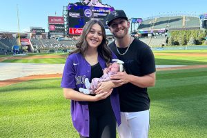 Mom and Dad hold baby Lainey on baseball field after she overcame congenital heart defects.