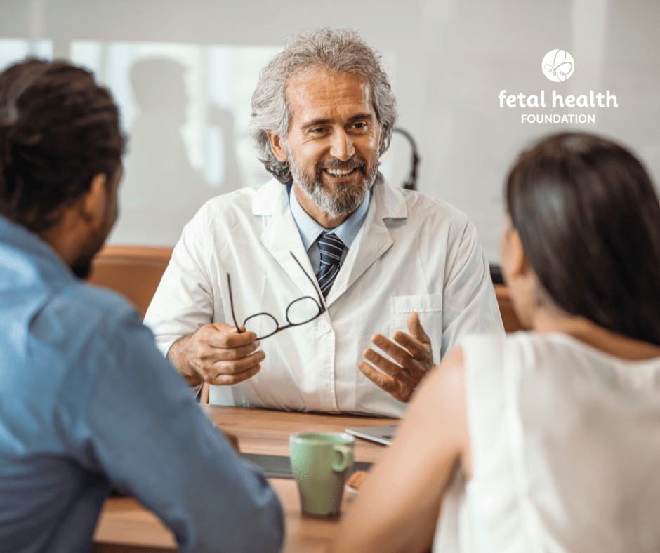 Male doctor discusses care with couple across a desk
